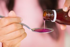 Woman,Hand,Pouring,Medication,Or,Antipyretic,Syrup,From,Bottle,To